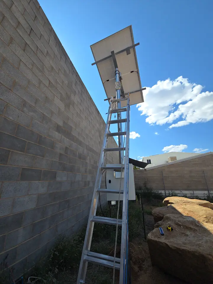 The solar panel mounted at the top of the pole, seen from a ladder