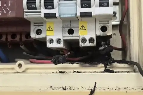 A switchboard with heat-damaged, burnt connections, the kind of fault an emergency call finds